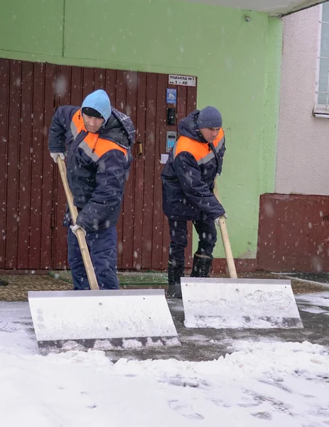 Werknemers in uniform met grote schoppen. Sneeuw verwijderen op de straten van de stad. — Stockfoto