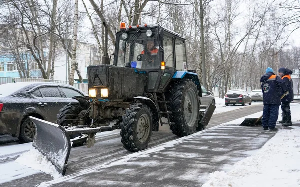 Tractor verwijdert sneeuw van de weg. Sneeuwruimen op straat. — Stockfoto
