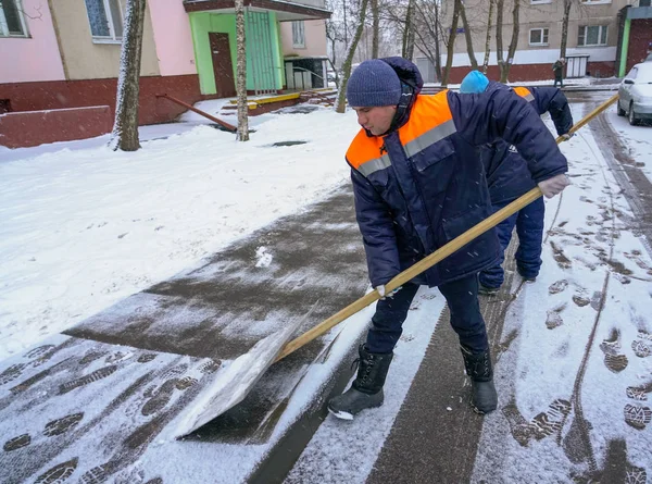 Trabajadores en uniforme con grandes palas. Eliminación de nieve en las calles de la ciudad . — Foto de Stock