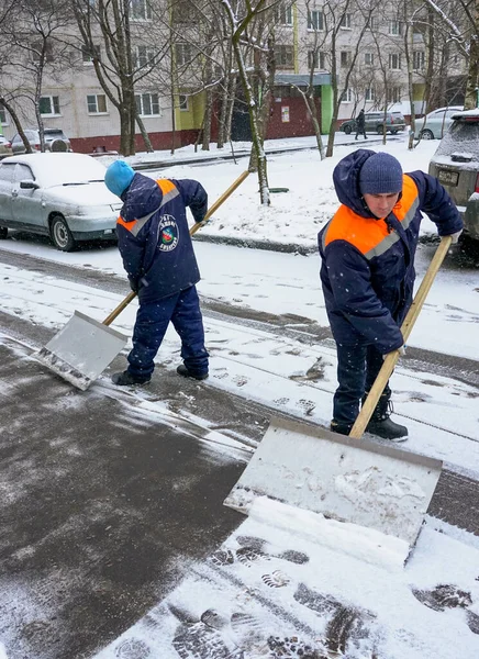 Arbeider i uniform med store spader. Snøfresing i bygatene . – stockfoto