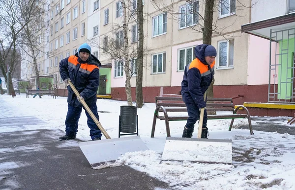 Trabalhadores fardados com pás grandes. Remoção de neve nas ruas da cidade . — Fotografia de Stock