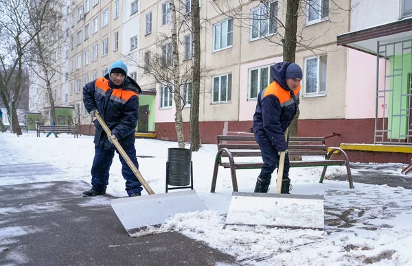 Werknemers in uniform met grote schoppen. Sneeuw verwijderen op de straten van de stad. — Stockfoto