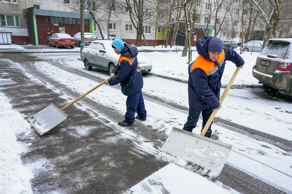 Werknemers in uniform met grote schoppen. Sneeuw verwijderen op de straten van de stad. — Stockfoto