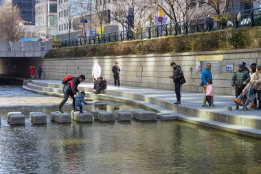 Seul, Mart 2019 Cheonggyecheon, Seul 'un merkezinde küçük bir nehir. Taştan bir köprü boyunca insanlar dereyi geçer..