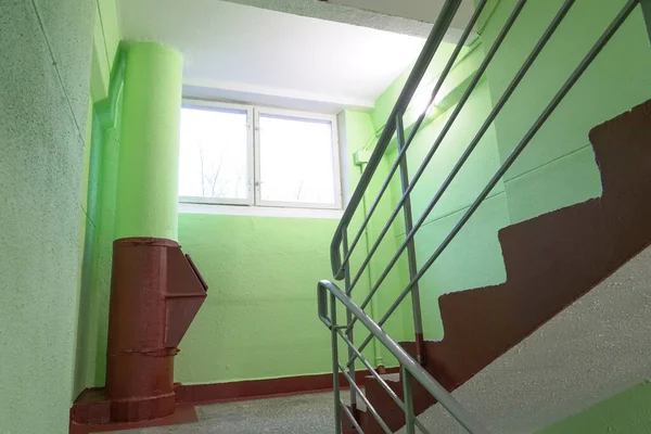 住宅公寓楼内设有垃圾槽的楼梯 墙壁上涂满了明亮的绿色油漆和窗户发出的光芒 — 图库照片