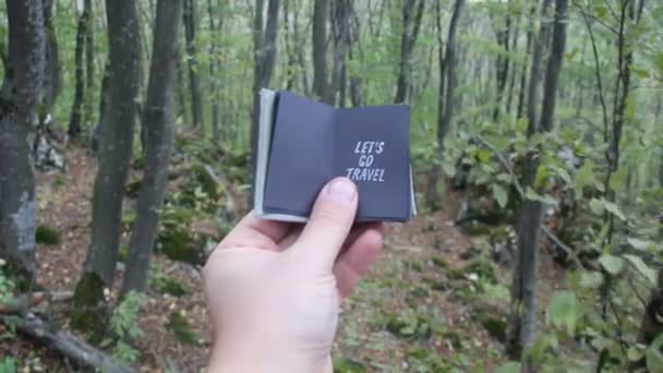 Hand holding a book with the inscription lets go travel — Stock Video