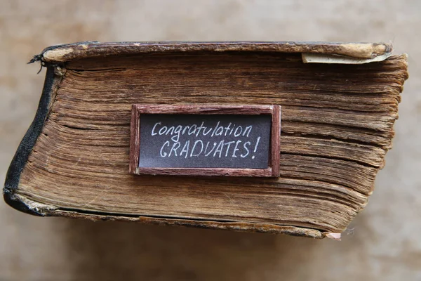 Felicitaciones graduados texto y libro vintage en la mesa —  Fotos de Stock