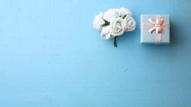 Розы с подарочной коробкой на синем фоне — стоковое видео