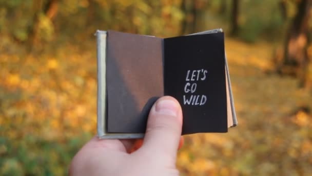 Lets go wild. Traveler holds a book with the inscription. Tourism motivation. — Stock Video