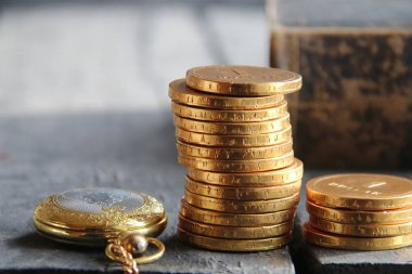 Altın sikke ve kitap yığını. İşletme veya Maliye kavramı.