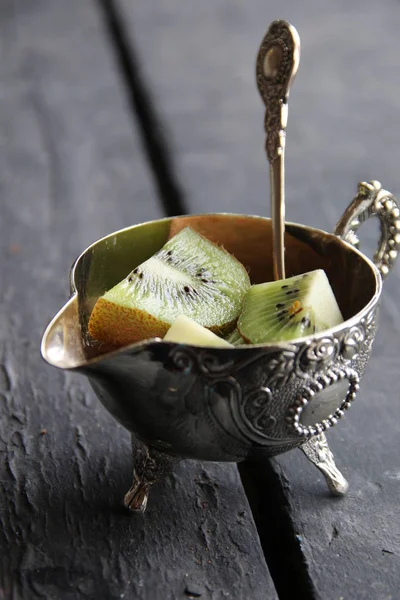 Postre con fruta kiwi en tazón de plata y cuchara. Fondo alimentario . — Foto de Stock