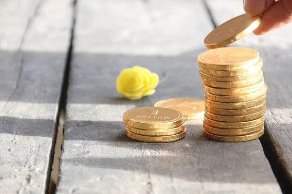 Monedas de pila con mano sobre mesa de madera Imagen de archivo