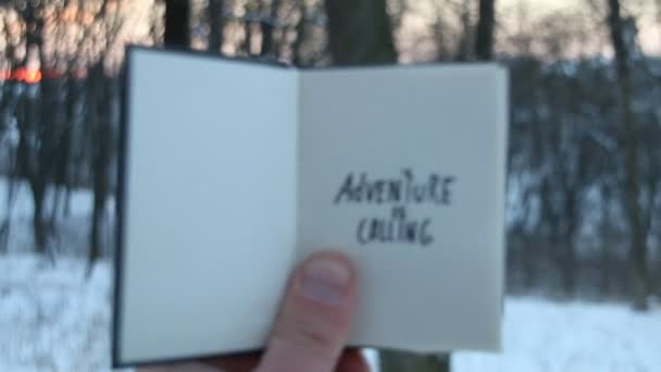La aventura es llamar, una idea de viaje. Libro y escrito a mano Letras de vacaciones de invierno . — Vídeo de stock