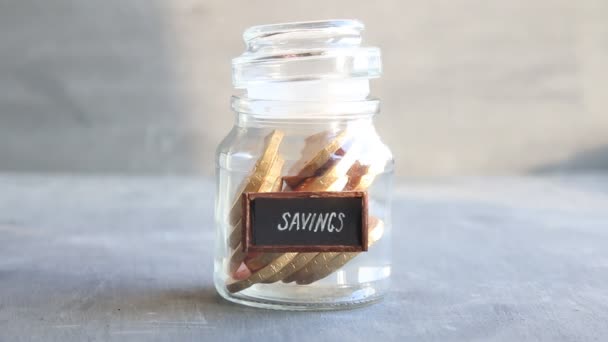 Ідея заощаджень, вінтажний тег і монети в банці — стокове відео