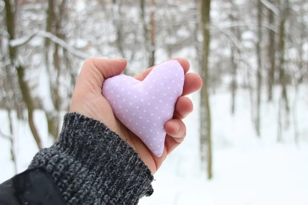 Hand holding a heart On the background of the snowy winter forest — Stock Photo, Image
