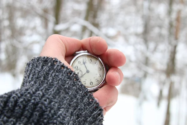 Vinter tid idé. Hand som håller ett fickur. På bakgrund av snöiga skogen. — Stockfoto