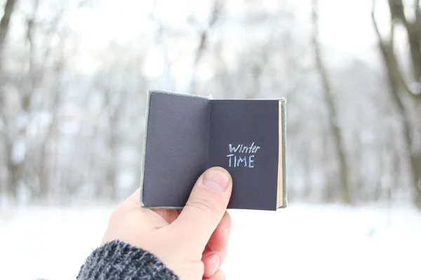 Zimowy czas pomysł, ręka trzyma książkę z tekstu na tle parku — Zdjęcie stockowe