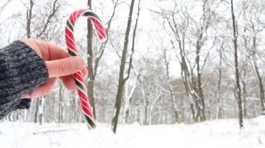 Candy Cane tutan el. Karlı Noel manzara. Fotoğraf arka plan bulanık.