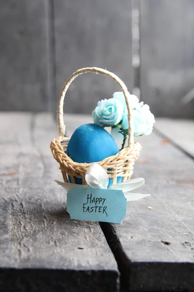 Frohe Ostern. blaues Ei auf rustikalem Tisch und ein Korb mit Anhänger. — Stockfoto