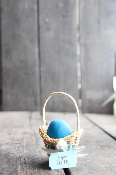 Frohe Ostern. blaues Ei auf rustikalem Tisch und ein Korb mit Anhänger. — Stockfoto