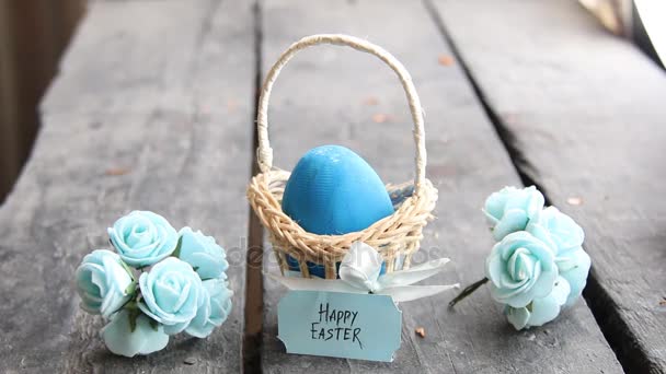 Щасливого Великодня. Яйце на сільському столі і кошик з синьою етикеткою — стокове відео
