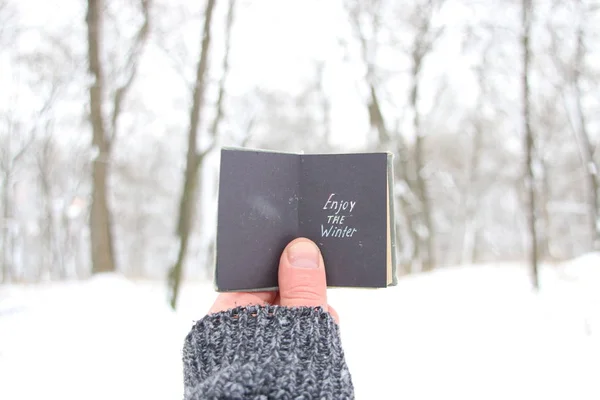 Enjoy the winter, man holding a book with the inscription — Stock Photo, Image