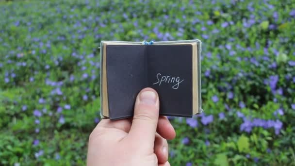 Concepto de primavera, libro con texto y campo de primavera con flores azules — Vídeos de Stock