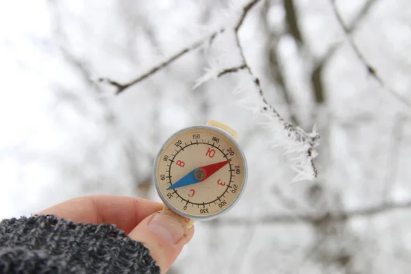 Traveler searching direction with a compass on background of winter forest — Stock Photo, Image