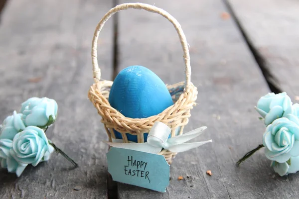 Frohe Ostern. blaues Ei auf rustikalem Tisch und ein Korb mit Anhänger. — Stockfoto