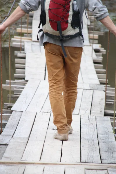 Turista e viajante caminhando em uma ponte suspensa de madeira — Fotografia de Stock