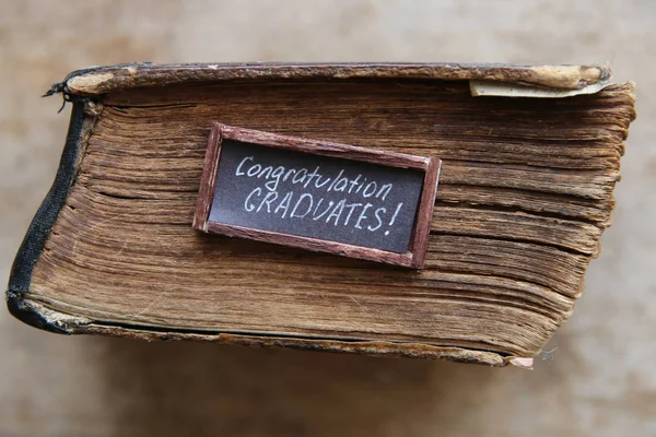 Felicitaciones graduados texto y libro vintage en la mesa — Foto de Stock