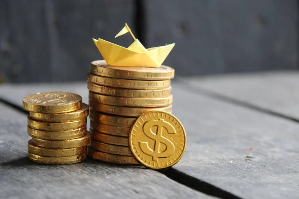 Graph of gold coins and a paper boat — Stockfoto