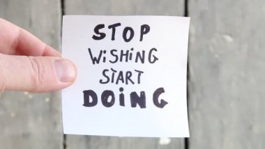 Dilemeyi bırak ve yapmaya başla. El üstünde yazı olan bir kağıt parçası tutuyor..