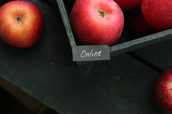 Internet, web service idea or Grocery online shop concept. Ripe red apples in wooden box and tag with the inscription online.