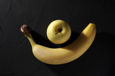 Siyah arkaplanda elma ve muz, yakın plan.