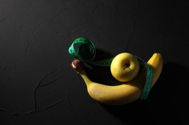 Siyah arka planda elmalı muz, taksimetre, sağlıklı beslenme kavramı.