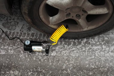 Kışın elektrikli pompayla araba tekerleğini şişirmek, yakın plan.