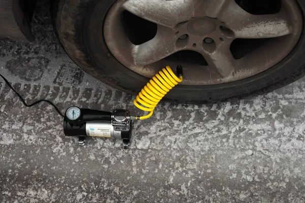 Kışın elektrikli pompayla araba tekerleğini şişirmek, yakın plan.