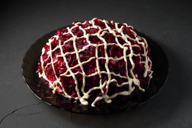 herring salad under a fur coat on a dark background