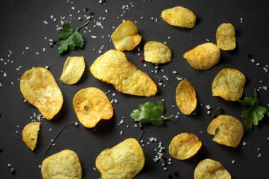 potato chips, pepper mixture, sea salt on a dark table