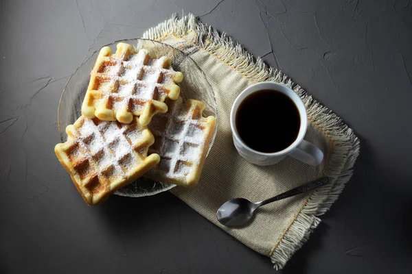 Şeffaf tabakta ev yapımı waffle 'lar ve ışıklı bir masada kahve fincanı.
