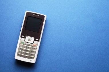 Metinleriniz için mavi arkaplan üzerinde eski bir cep telefonu