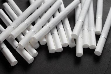 Beyaz filtreli sigaralar koyu beton arka planda, yumuşak odaklı.