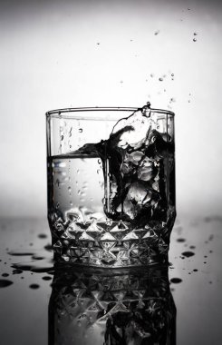 Buz küpü bir bardak suya atılır, su damlaları bir bardak sudan uçar.