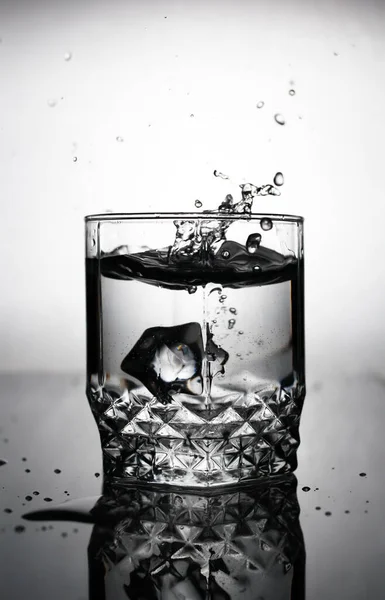 Ein Eiswürfel Wird Ein Glas Wasser Geworfen Wasserspritzer Fliegen Aus — Stockfoto