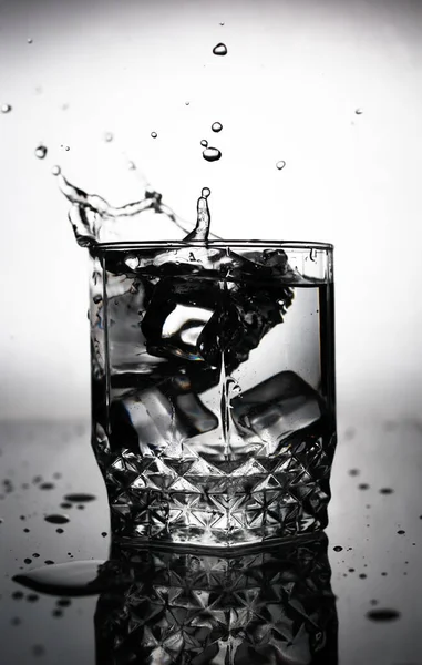 Ein Eiswürfel Wird Ein Glas Wasser Geworfen Wasserspritzer Fliegen Aus — Stockfoto