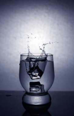 Buz küpleri fırlatırken bardaktan su sıçratıyor.