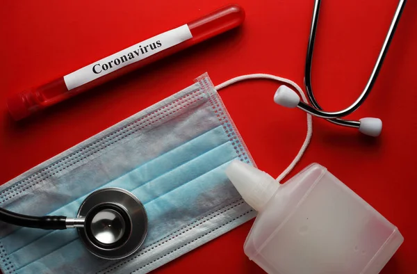 Tıbbi maske, tıbbi fonendoskop, antiseptik, kırmızı arka planda kan olan test tüpü.