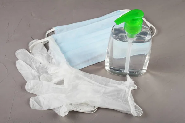 Coronavirus kavramı, tek kullanımlık eldivenler, tıbbi maskeler ve antiseptikler gri arka planda yatar