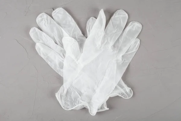 White disposable gloves on a gray background.